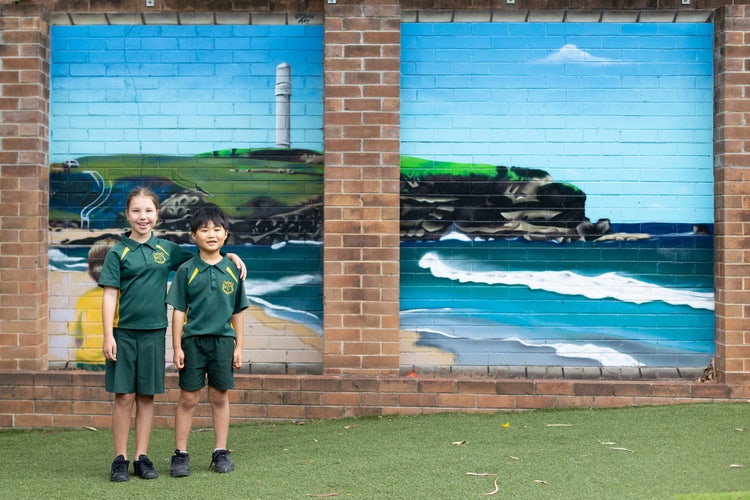 Two students standing in front of our beach mural.
