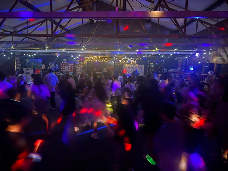 Students dancing at a disco with disco lights.